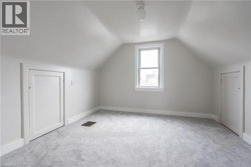 Attic room featuring a single window, two panel doors, sloped ceilings, and light gray carpeting - 156 Adeline Avenue, Hamilton, ON 