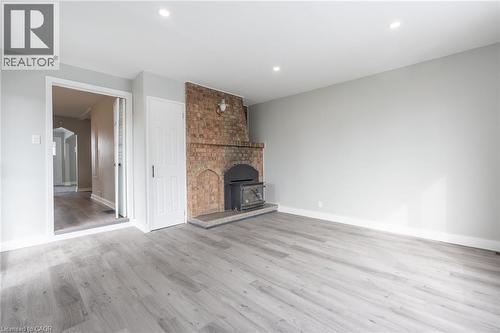 Spacious room featuring light gray walls and wood-finish flooring - 156 Adeline Avenue, Hamilton, ON - Indoor Photo Showing Other Room With Fireplace