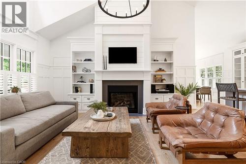 Vaulted ceiling living area featuring a fireplace with built-in shelving, hardwood flooring, and white plantation shutters - 330 Camelot Court, Burlington, ON - Indoor Photo Showing Living Room With Fireplace