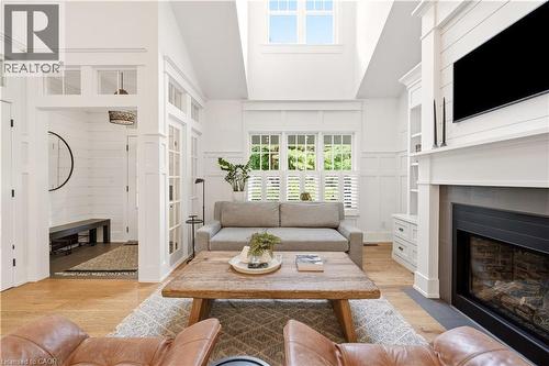 Spacious living area featuring light wood-finish flooring and extensive white paneling - 330 Camelot Court, Burlington, ON - Indoor Photo Showing Living Room With Fireplace