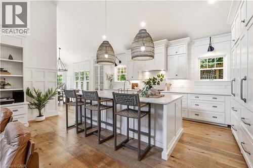 Gourmet kitchen featuring a substantial island with seating, white shaker cabinetry, stone countertops, and wood-finish flooring - 330 Camelot Court, Burlington, ON - Indoor