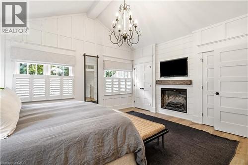 Vaulted ceiling room featuring a decorative chandelier, white paneling, and wood-finish flooring - 330 Camelot Court, Burlington, ON - Indoor Photo Showing Bedroom With Fireplace