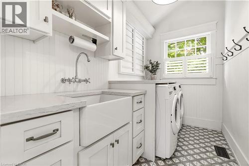 White shaker cabinetry with a large farmhouse sink, wall-mounted faucet, and light-toned countertops - 330 Camelot Court, Burlington, ON - Indoor Photo Showing Laundry Room