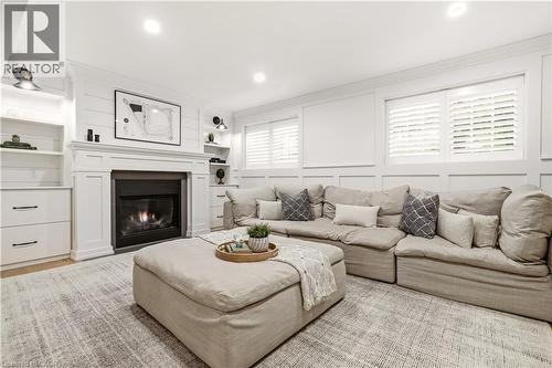 Living area featuring a fireplace with a white mantel, built-in shelving, white plantation shutters, white paneled walls, and recessed lighting - 330 Camelot Court, Burlington, ON - Indoor Photo Showing Living Room With Fireplace