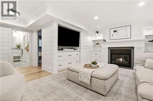 Living area featuring a fireplace with a mantel, built-in shelving, wood-finish flooring, and shiplap wall accents - 330 Camelot Court, Burlington, ON - Indoor Photo Showing Living Room With Fireplace