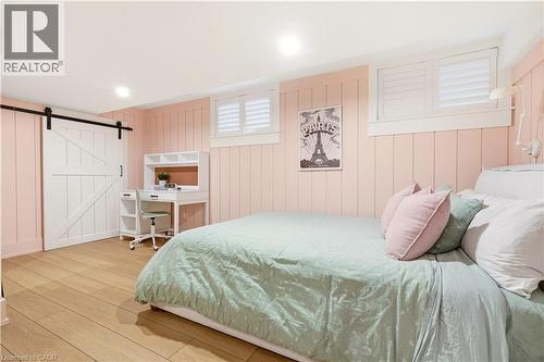 Spacious room featuring light wood-finish flooring, vertical paneling, and a white barn door - 330 Camelot Court, Burlington, ON - Indoor Photo Showing Bedroom
