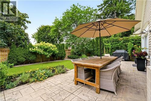 Stamped concrete patio with a wood-finish dining table and woven seating - 330 Camelot Court, Burlington, ON - Outdoor
