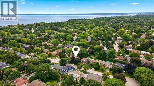 Aerial perspective showcasing a residential area with extensive tree canopies, numerous detached homes, and a prominent body of water in the background - 330 Camelot Court, Burlington, ON - Outdoor With Body Of Water With View
