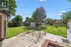 Spacious backyard featuring a concrete patio, a metal gazebo frame, and perimeter fencing - 