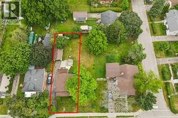 Aerial perspective showcasing a residential property with a brown-roofed structure, featuring a paved driveway, a detached garage, and a substantial grassy backyard - 