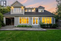 Gray siding exterior with multiple dormer windows, a covered patio, and a stone-paver patio - 