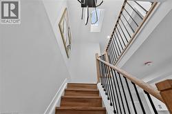 Staircase featuring wood-finish treads, light-toned wood handrails, and black metal balusters - 