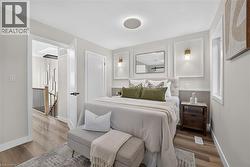 Light-filled room featuring wood-finish flooring, a contemporary ceiling light fixture, a built-in wall sconce, and a framed mirror - 