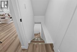 Stairwell featuring wood-finish flooring with metallic stair nosing, white baseboards, and bright white walls - 