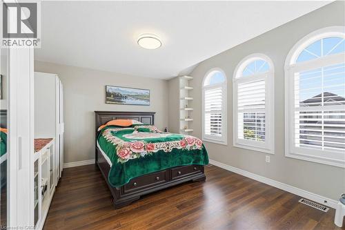 Bedroom featuring three arched windows with plantation shutters, wood-finish flooring, and a built-in shelving unit - 212 Chartwell Circle, Hamilton, ON - Indoor Photo Showing Bedroom