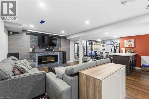 Recreation room featuring a stacked stone fireplace with LED lighting, a built-in media console, wood-finish flooring, and recessed ceiling lights - 212 Chartwell Circle, Hamilton, ON - Indoor Photo Showing Living Room With Fireplace