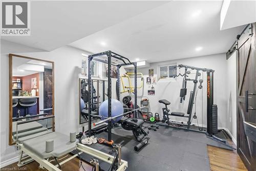 Dedicated fitness area featuring recessed lighting, light gray walls, dark wood-finish flooring, a barn door, and a mirrored wall - 212 Chartwell Circle, Hamilton, ON - Indoor Photo Showing Gym Room