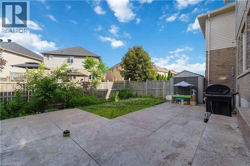 Expansive backyard featuring a concrete patio, a privacy fence, a storage shed, and mature trees - 212 Chartwell Circle, Hamilton, ON - Outdoor