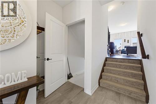 Entryway featuring light-toned tile flooring, white trim, and a staircase with carpeted treads and a wood handrail - 324 Equestrian Way Unit# 49, Cambridge, ON - Indoor Photo Showing Other Room