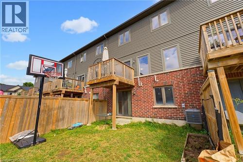 Exterior featuring wood siding, brick façade, multiple windows, a ground-level patio door, and an elevated wooden deck - 324 Equestrian Way Unit# 49, Cambridge, ON - Outdoor With Deck Patio Veranda