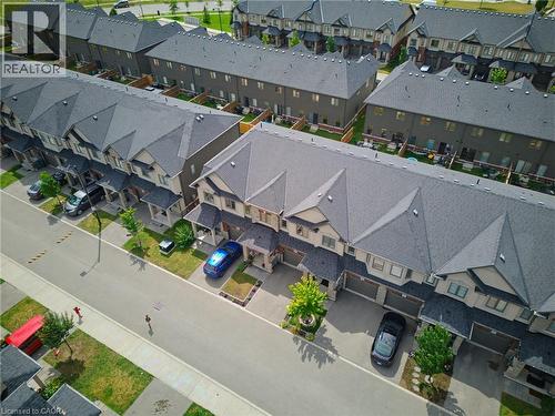 Row of townhomes featuring attached single-car garages, individual driveways, and covered front entrances - 324 Equestrian Way Unit# 49, Cambridge, ON - Outdoor With View
