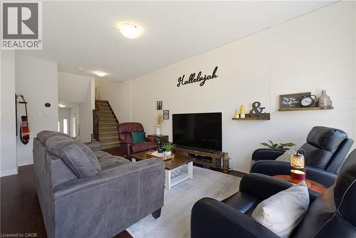 Open-concept living area featuring a prominent shiplap accent wall, dark wood-finish flooring, and a staircase with coordinating risers - 324 Equestrian Way Unit# 49, Cambridge, ON - Indoor Photo Showing Living Room