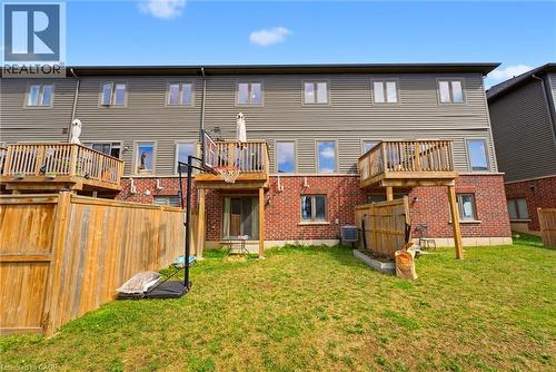 Expansive green lawn with a wooden privacy fence and a red brick lower facade - 324 Equestrian Way Unit# 49, Cambridge, ON - Outdoor With Deck Patio Veranda With Exterior