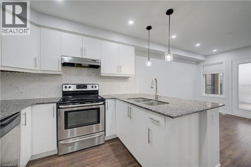 Modern kitchen featuring white cabinetry, stainless steel appliances, granite countertops, and wood-finish flooring - 911 Apple Hill Lane, Kitchener, ON - Indoor Photo Showing Kitchen With Stainless Steel Kitchen With Double Sink With Upgraded Kitchen