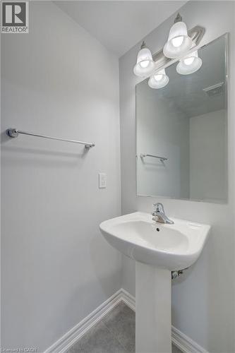Pedestal sink with chrome faucet, large vanity mirror, and three-bulb vanity light fixture - 911 Apple Hill Lane, Kitchener, ON - Indoor Photo Showing Bathroom