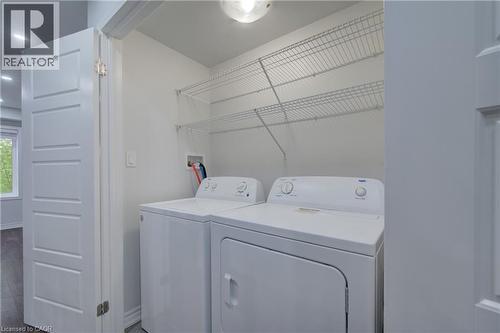 Dedicated laundry area featuring a white top-load washer, a white front-load dryer, and two levels of wire shelving - 911 Apple Hill Lane, Kitchener, ON - Indoor Photo Showing Laundry Room