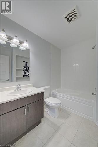 Bathroom featuring a white bathtub, toilet, and a vanity with a white countertop and integrated sink - 911 Apple Hill Lane, Kitchener, ON - Indoor Photo Showing Bathroom