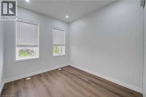 Bright room with wood-finish flooring and two windows featuring white blinds - 911 Apple Hill Lane, Kitchener, ON - Indoor Photo Showing Other Room