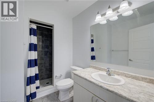 Bathroom featuring a walk-in shower with dark tile surround and a single vanity with an integrated sink and light-colored countertop - 911 Apple Hill Lane, Kitchener, ON - Indoor Photo Showing Bathroom