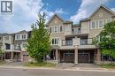 Contemporary townhome exterior featuring light-colored siding, brick accents, multiple balconies with glass railings, and individual garage access - 911 Apple Hill Lane, Kitchener, ON  - Outdoor With Balcony With Facade 