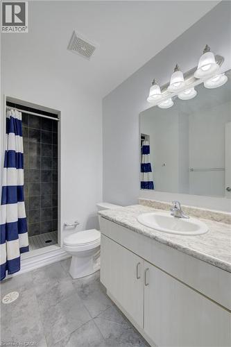Bathroom featuring a vanity with a white countertop and integrated sink, a large mirror with a five-light fixture, a toilet, and a walk-in shower with dark tile surround - 911 Apple Hill Lane, Kitchener, ON - Indoor Photo Showing Bathroom