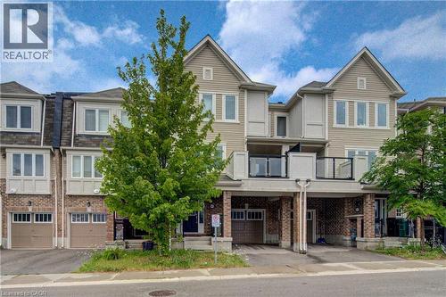 Three-story townhome with tan siding and brick accents - 911 Apple Hill Lane, Kitchener, ON - Outdoor With Balcony With Facade