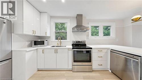 Contemporary kitchen featuring white cabinetry, light-toned countertops, stainless steel appliances, a brushed gold faucet, and light wood-finish flooring - 59 Longwood Road N, Hamilton, ON - Indoor Photo Showing Kitchen With Stainless Steel Kitchen