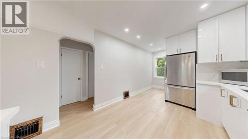 Bright kitchen area featuring light wood-finish flooring, recessed lighting, and white cabinetry with gold-tone hardware - 59 Longwood Road N, Hamilton, ON - Indoor Photo Showing Kitchen
