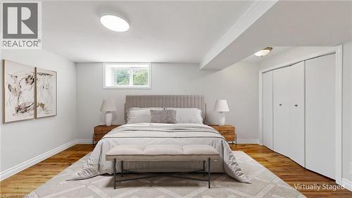 Room featuring wood-finish flooring, white baseboards, a white window frame, and bi-fold closet doors - 59 Longwood Road N, Hamilton, ON - Indoor Photo Showing Bedroom