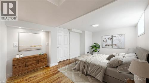 Bright interior space featuring wood-finish flooring, white walls, and a white paneled door - 59 Longwood Road N, Hamilton, ON - Indoor Photo Showing Bedroom