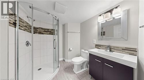 Bathroom featuring a curved glass shower enclosure, white subway tile with an accent mosaic band, a built-in vanity with a rectangular sink, a framed mirror, and a three-light vanity fixture - 59 Longwood Road N, Hamilton, ON - Indoor Photo Showing Bathroom