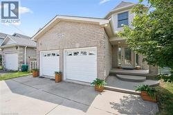 Brick and siding exterior featuring a two-car garage with panel doors, a concrete driveway, and a covered entry with a glass-paneled door - 