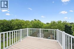 Expansive outdoor deck featuring wood-finish flooring and a white railing system with integrated glass panels - 