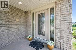 Front entry featuring a light-colored brick facade, a recessed overhead light, and a white entry door with decorative glass paneling - 