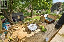 Multi-level wood deck featuring a built-in hot tub with privacy screens, steps, and a spacious lower patio area - 