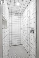 Tiled shower enclosure featuring white square wall tiles and hexagonal floor tiles - 