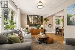 Light-filled living area featuring a large bay window, wood-finish flooring, and an open layout - 