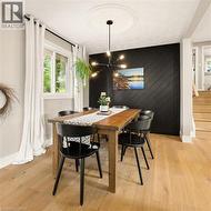 Dining area featuring a striking accent wall with diagonal wood-finish planks, light wood-finish flooring, and a contemporary multi-bulb chandelier with a ceiling medallion - 