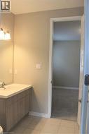Bathroom vanity featuring a light wood-finish cabinet with double doors, an integrated countertop sink, and a mirrored backsplash - 