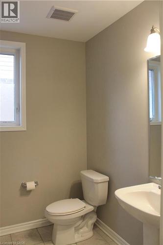 Bathroom featuring a white toilet, pedestal sink, ceramic tile flooring, and a single window - 31 Pointer Street Unit# Main Floor, Cambridge, ON - Indoor Photo Showing Bathroom